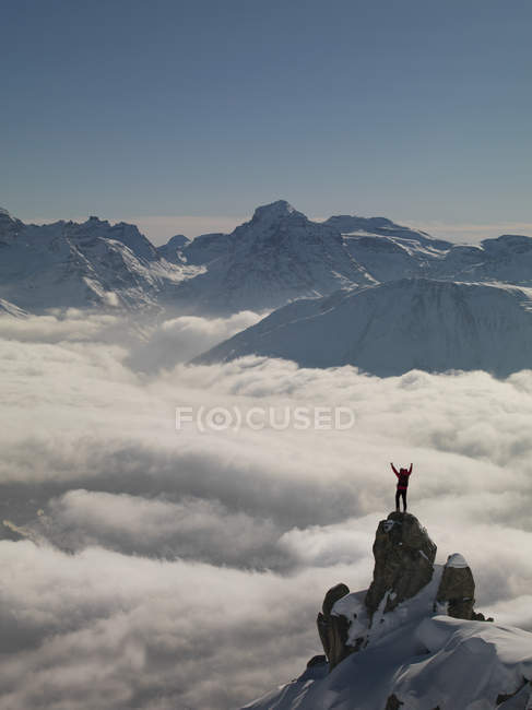 Climber celebrating on peak emerging from fog, Bettmeralp, Valais, Switzerland — Stock Photo