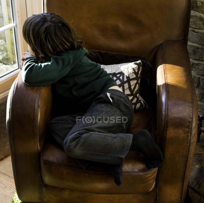 Мальчик отдыхает на кресле после школы — стоковое фото