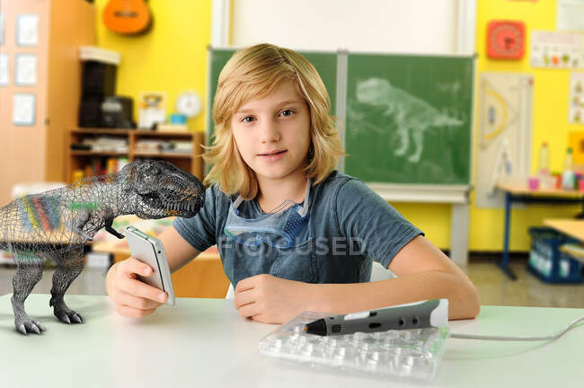 Retrato de menino com computador de mão e modelo 3D de tiranossauro rex — Fotografia de Stock