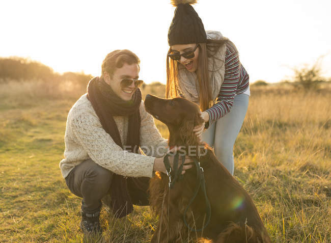 Giovane coppia che gioca con il cane in campo — Foto stock