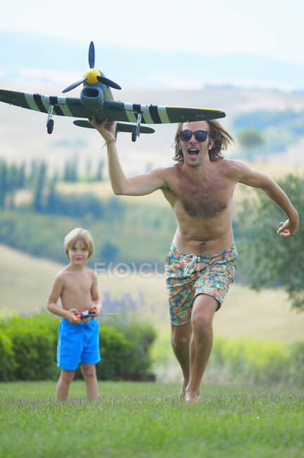 Father and son flying remote control plane, outdoors — Stock Photo