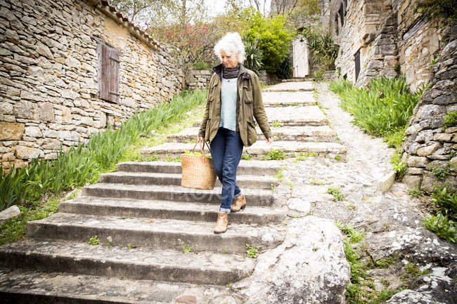 Woman walking down steps, Bruniquel, Francia - foto de stock