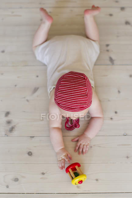 Bebê menina deitada no chão com brinquedo — Fotografia de Stock