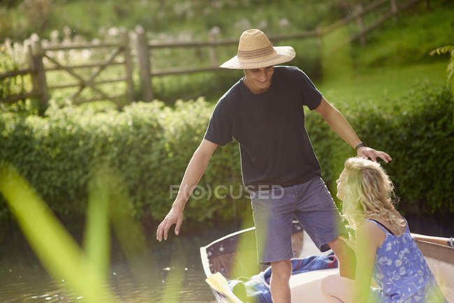Young man with girlfriend standing in rowing boat on river — Stock Photo