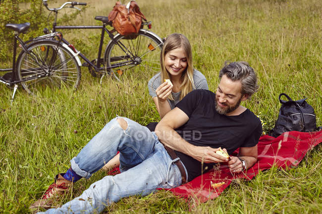 Couple mangeant des pommes au pique-nique dans un champ rural — Photo de stock