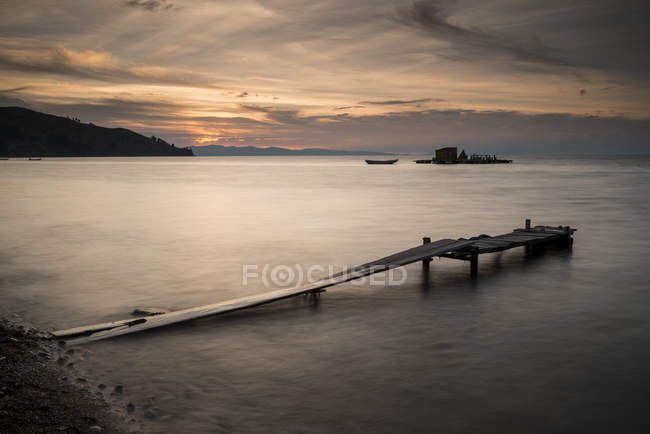 Long exposure shot of pier on beach at sunset — Stock Photo