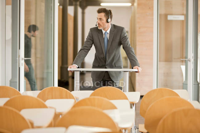 Homem de negócios usando fone de ouvido no pódio — Fotografia de Stock