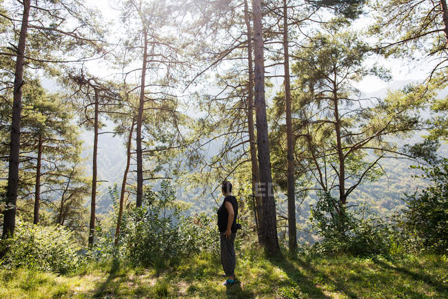 Mujer de pie en el bosque mirando hacia otro lado, Passo Maniva, Italia - foto de stock