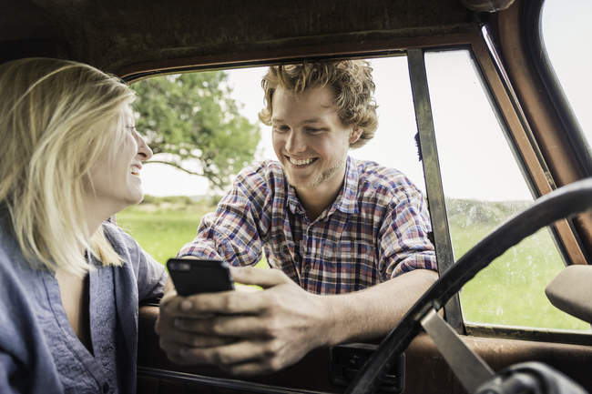 Junger Mann mit Freundin liest Smartphone-Texte am Jeep-Fenster — Stockfoto
