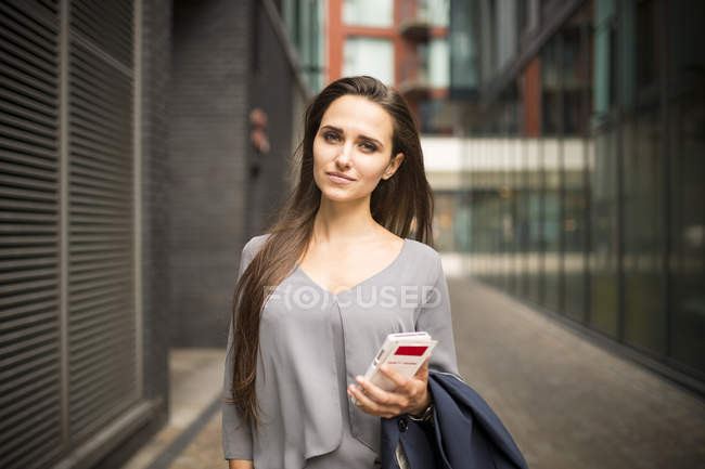 Jeune femme d'affaires avec smartphone à l'extérieur du bureau, Londres, Royaume-Uni — Photo de stock