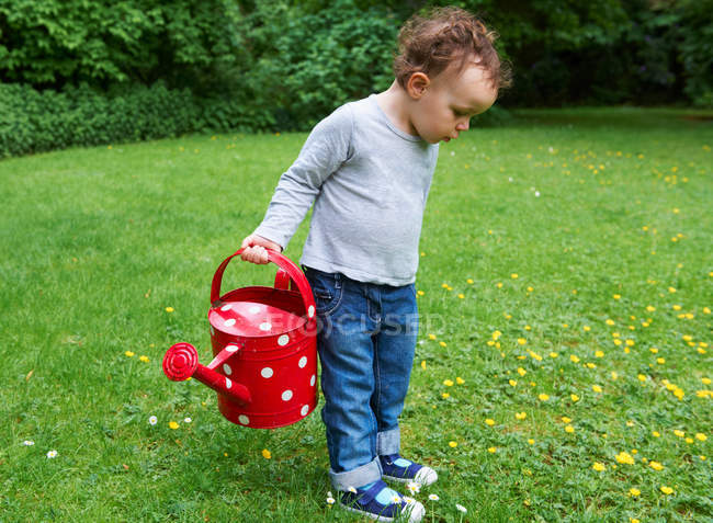 Toddler boy carrying watering can — Stock Photo