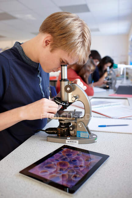 Estudiante usando microscopio en clase - foto de stock
