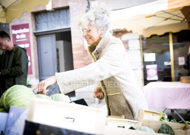 Maduro feminino comprador compra legumes no local francês mercado — Fotografia de Stock