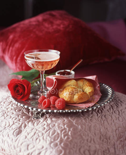 Vassoio in argento con bicchiere di champagne rosa, croissant e lamponi — Foto stock