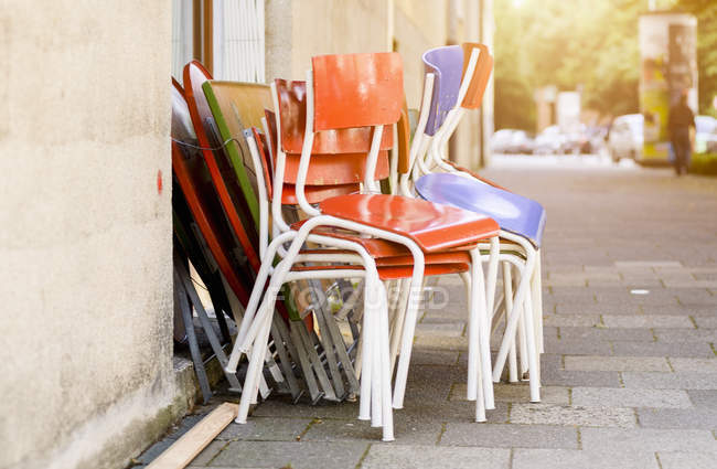 Colorful chairs stacked beside building wall — Stock Photo