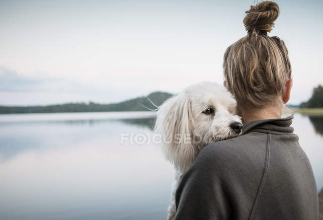 Coton de tulear dog looking over women's shoulder at lake, Orivesi, Finlande — Photo de stock