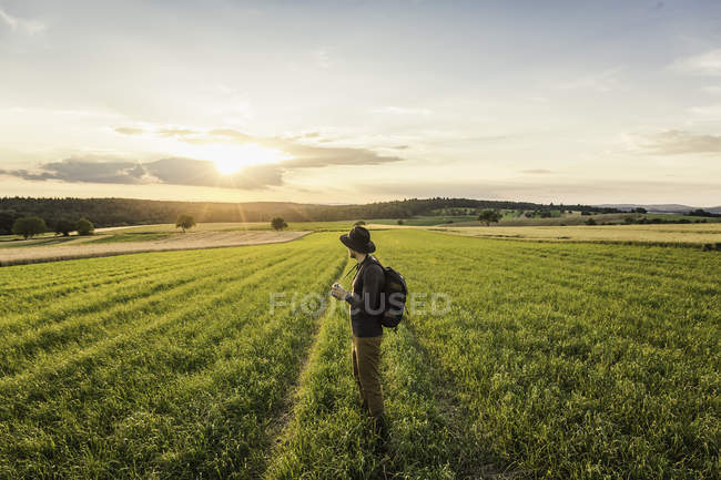 Hombre adulto, de pie en el campo, sosteniendo la cámara SLR, mirando a la vista, Neulingen, Baden-W? rttemberg, Alemania - foto de stock