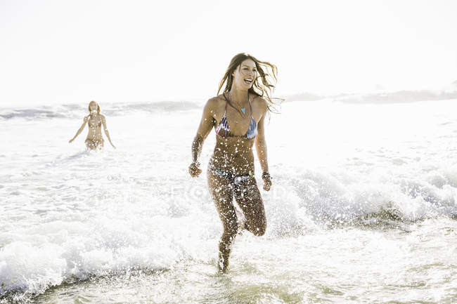 Two women wearing bikinis running in sea, Cape Town, South Africa — Stock Photo