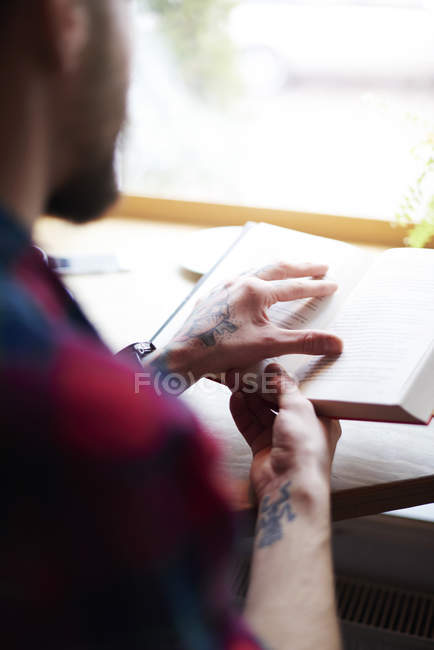 Over shoulder view of man reading book — Stock Photo