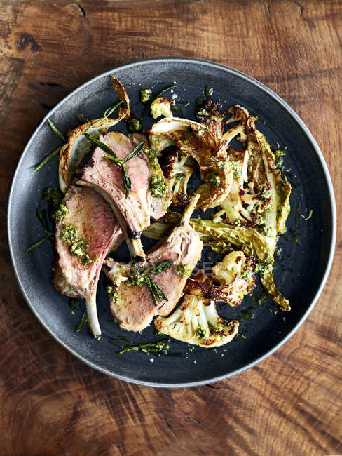 Top view of lamb cutlets on dish with roasted cauliflower and rosemary — Stock Photo