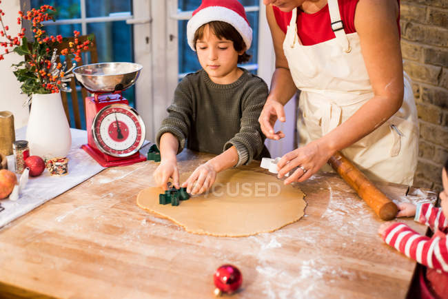 Мать и сын пекут рождественское печенье дома — стоковое фото