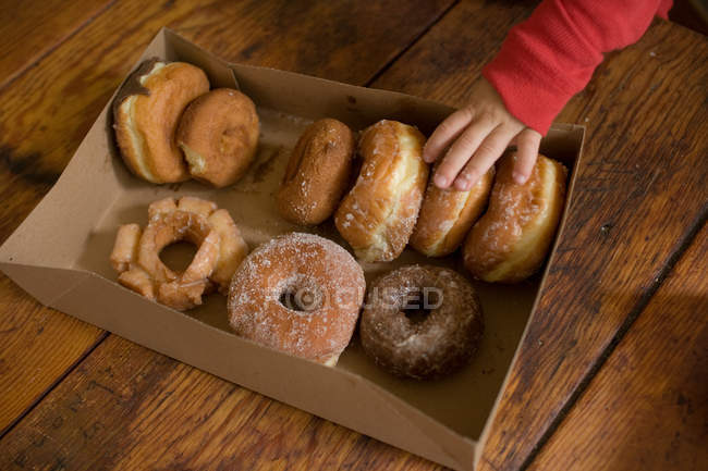 Toddler boy taking doughnut from box, cropped shot — Stock Photo