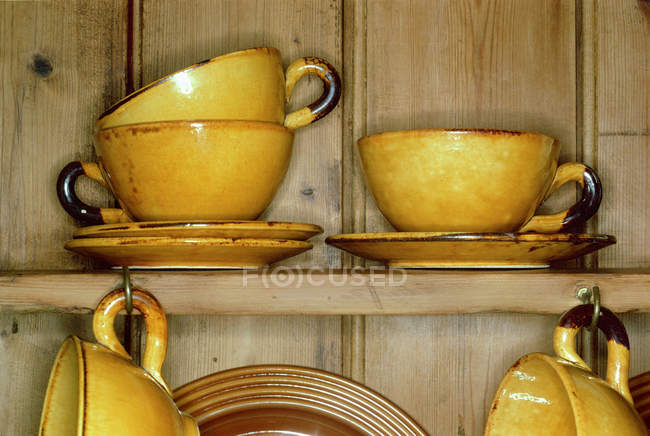 Желтые чашки и блюдца в шкафу — стоковое фото