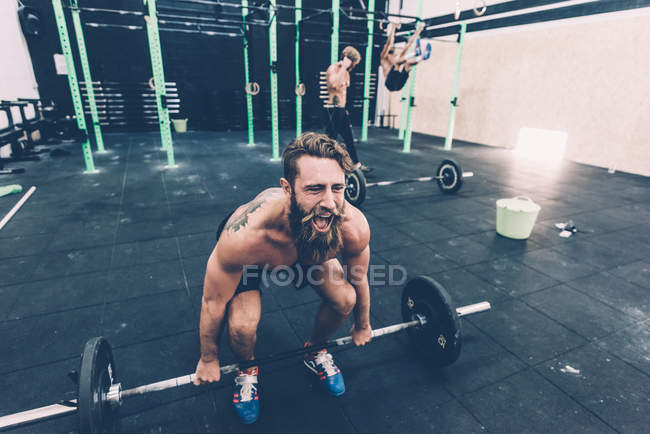 Jeune homme cross trainer se préparant à soulever haltère dans la salle de gym — Photo de stock