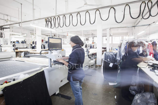 Female factory worker operating manufacturing machine in clothing factory — Stock Photo