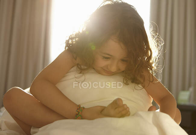 Girl on bed holding foot — Stock Photo