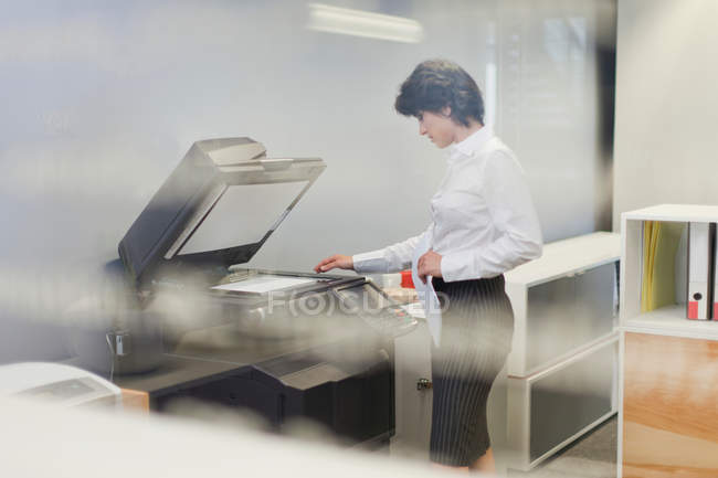Businesswoman making copies in office — Stock Photo