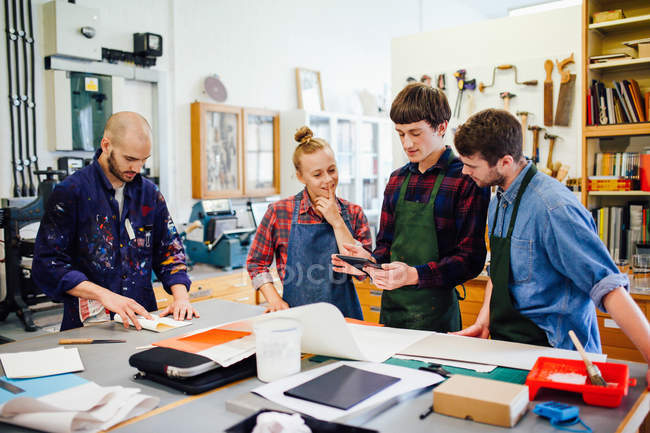 Group of young craftspeople using digital tablet in book arts workshop — Stock Photo
