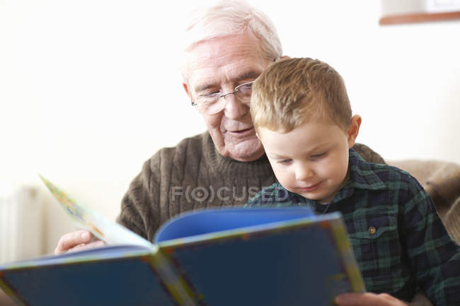 Старший читает книгу внуку — стоковое фото