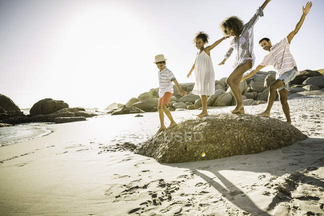 Padres e hijos balanceándose sobre roca - foto de stock