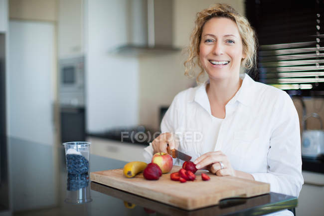 Mulher corte de frutas na cozinha — Fotografia de Stock