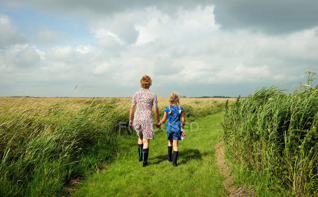 Vista trasera de la madre y la hija caminando en el campo - foto de stock