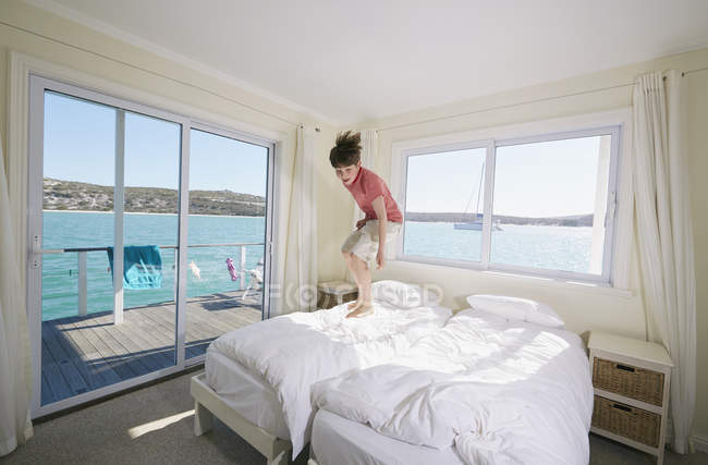 Boy jumping on bed in houseboat, Kraalbaai, South Africa — Stock Photo
