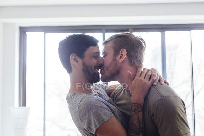 Couple masculin à la maison, s'amuser, s'embrasser et rire — Photo de stock