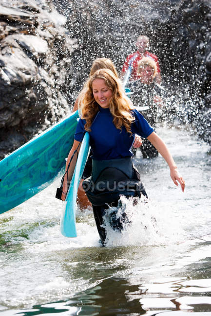 Four people carrying surfboards — Stock Photo