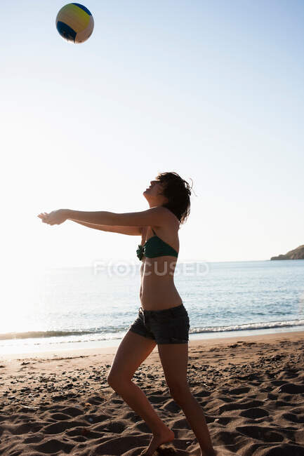 Mulher jogando com vôlei na praia — Fotografia de Stock
