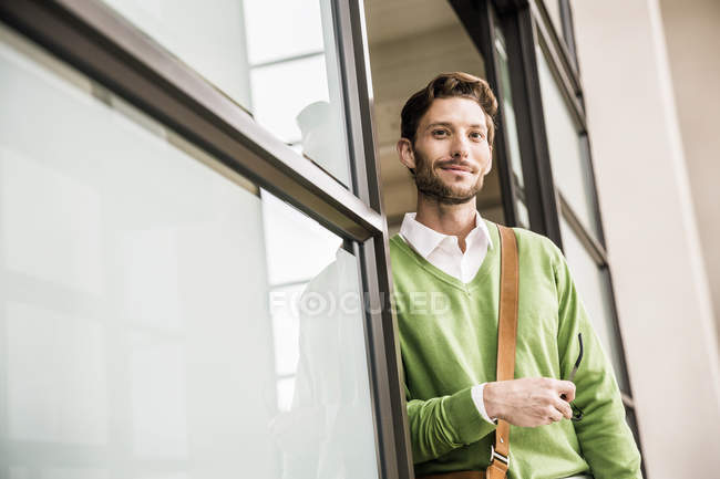 Портрет крутого впевненого бізнесмена, що спирається на офісні двері — стокове фото
