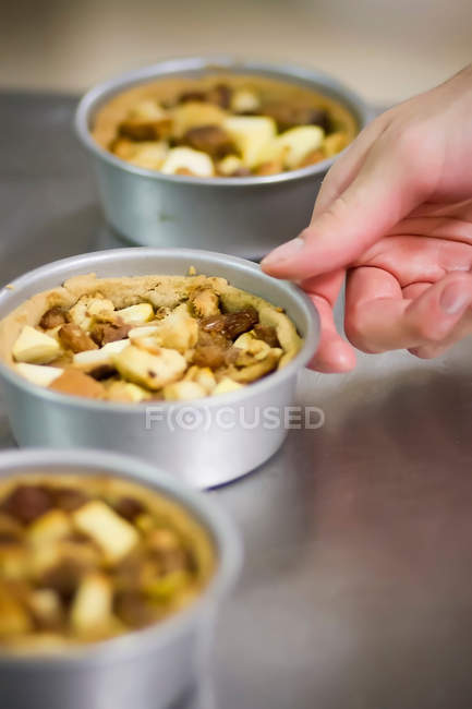 Cropped image of Baker with tins of nut cakes — Stock Photo
