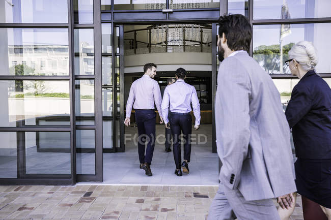 Empresarios y mujeres que llegan al edificio de oficinas - foto de stock