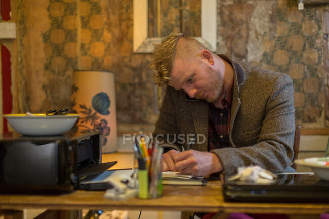 Businessman taking notes at desk — Stock Photo