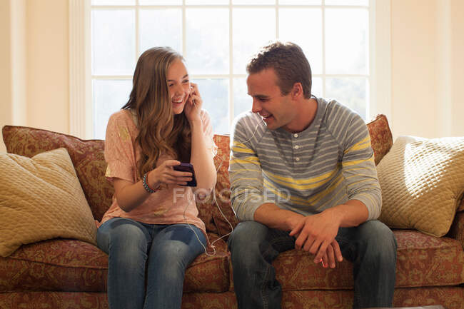 Брат и сестра на диване с наушниками — стоковое фото