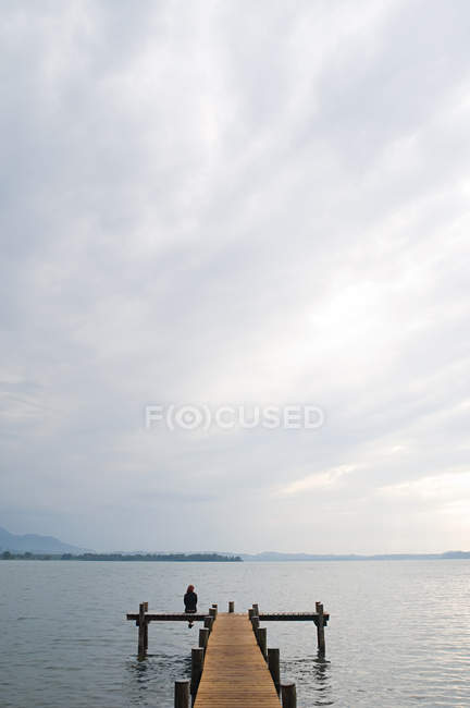 Woman sitting on a jetty at the lake — Stock Photo