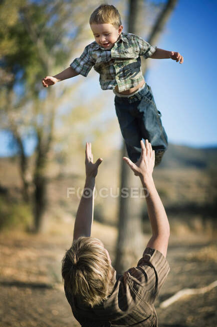 Батько кидає молодого сина в повітря — стокове фото