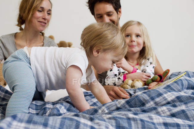 Маленькая девочка ползает по кровати родителей — стоковое фото
