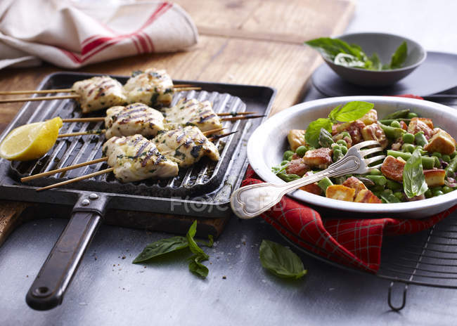 Chargrilled snapper skewers with lemon and bowl of salad — Stock Photo