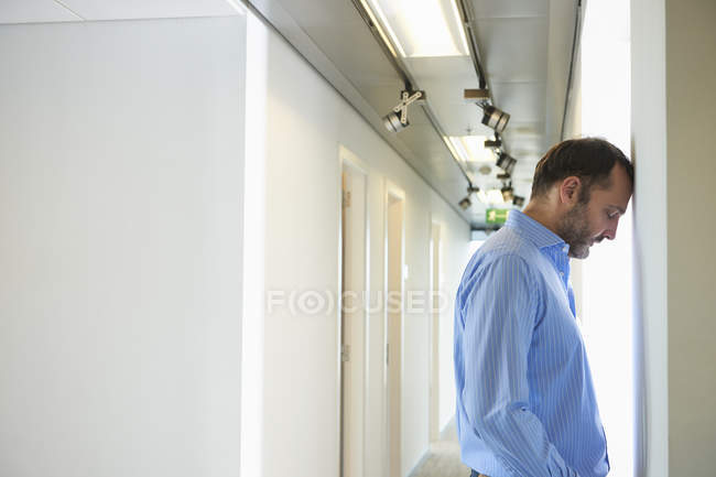 Uomo maturo appoggiato testa contro parete in corridoio — Foto stock